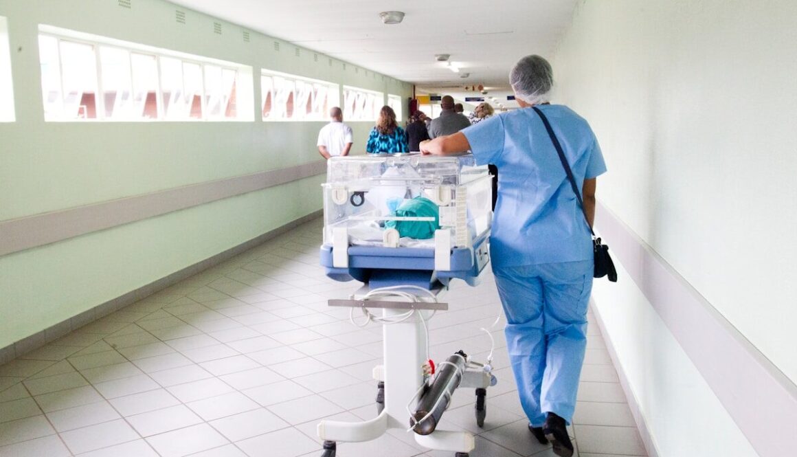 person walking on hallway in blue scrub suit near incubator
