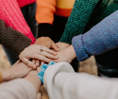 group stacking hands in colorful sweaters